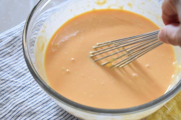 牛乳とレモン汁を加え泡だて器を添えたチーズケーキ生地