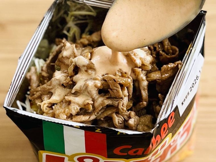ピザポテトの袋に、千切りキャベツ、ソース、豚肉を入れている様子