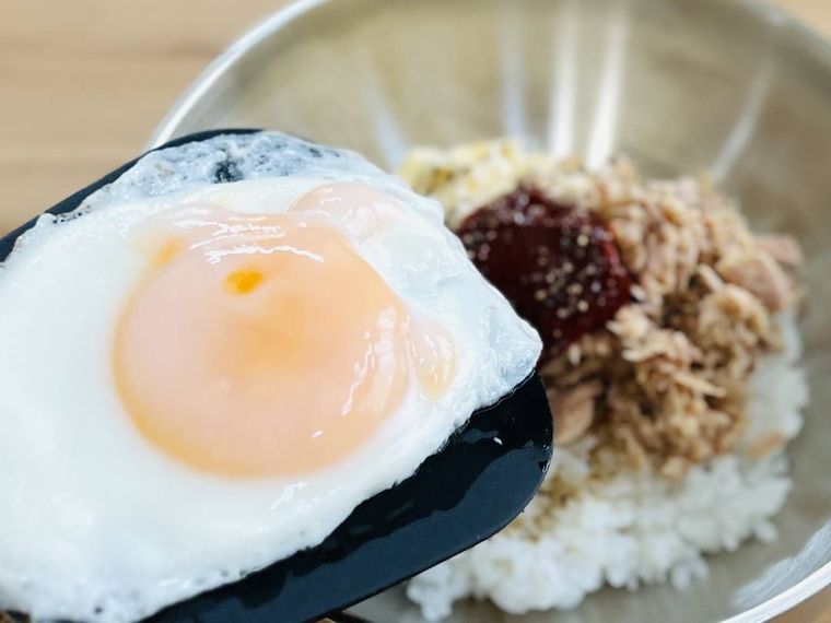 ツナマヨビビンバに目玉焼きをトッピングしている様子