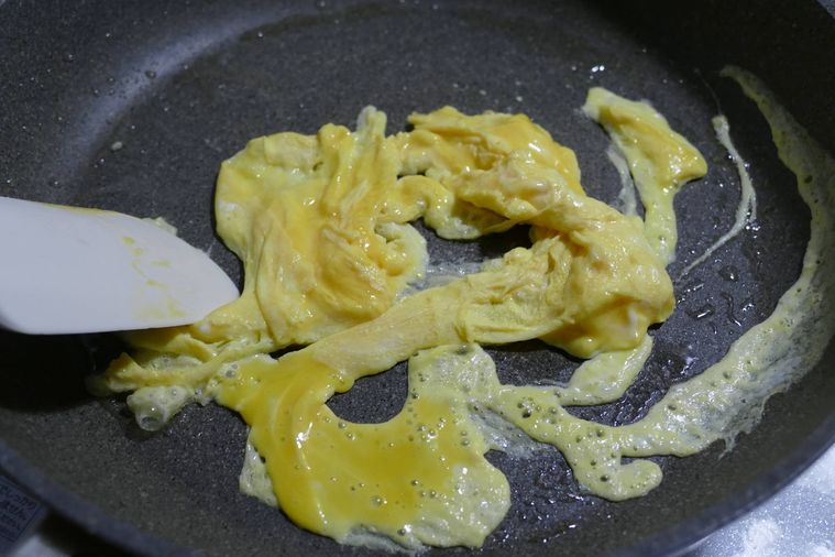ヘラで卵を混ぜながら炒める様子