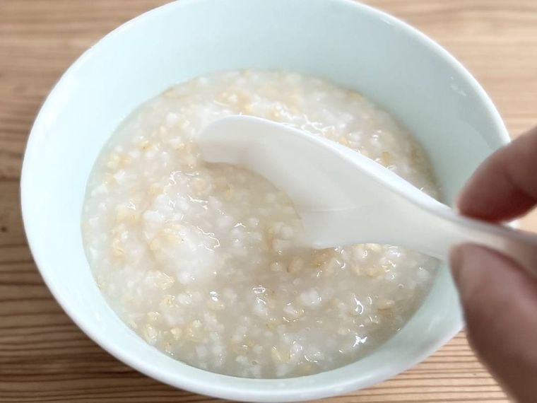 お粥に鶏ガラスープの素を混ぜている様子