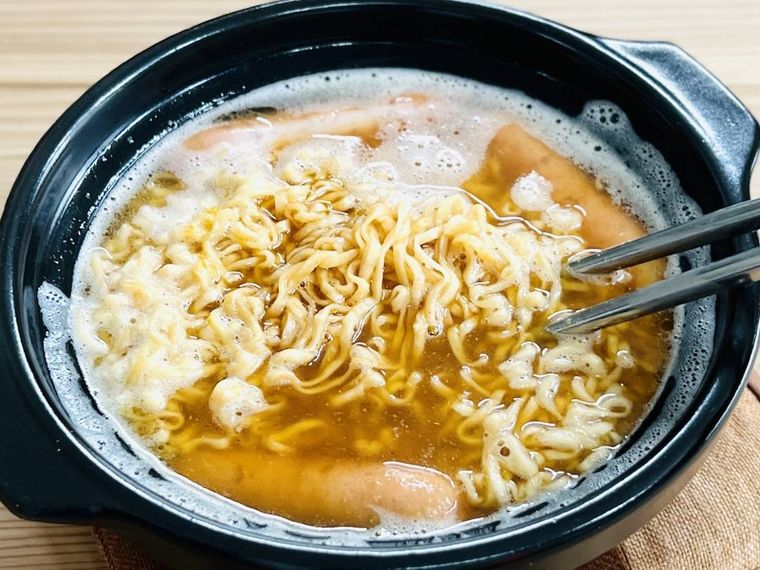 ウインナーとカレー粉が入ったチキンラーメンをかき混ぜている様子