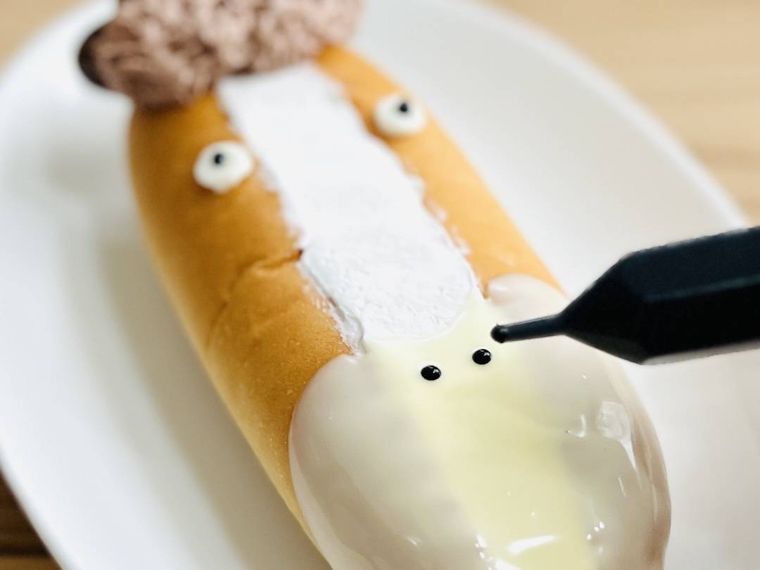 ホットドッグパンにチョコペンで馬の表情を描いている様子