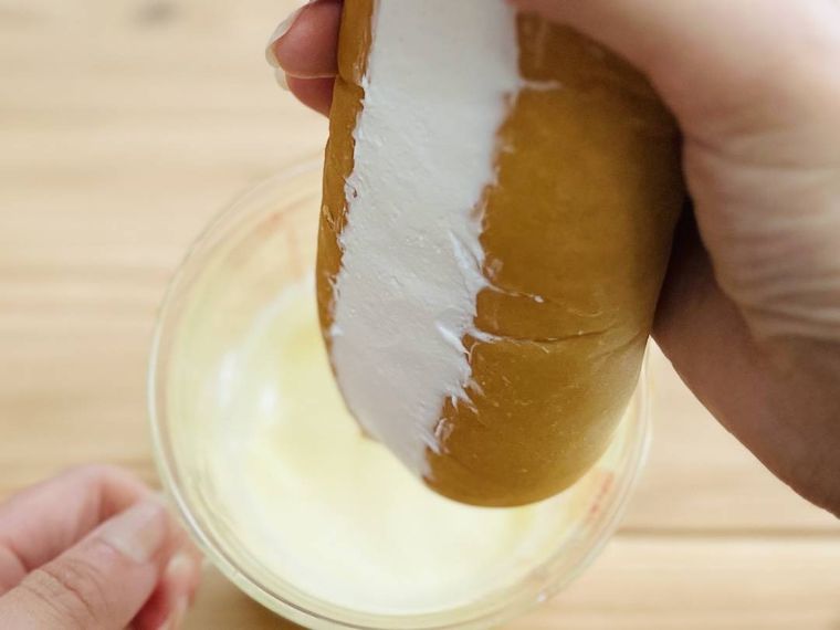 溶かしたホワイトチョコレートにパンを浸そうとしている様子