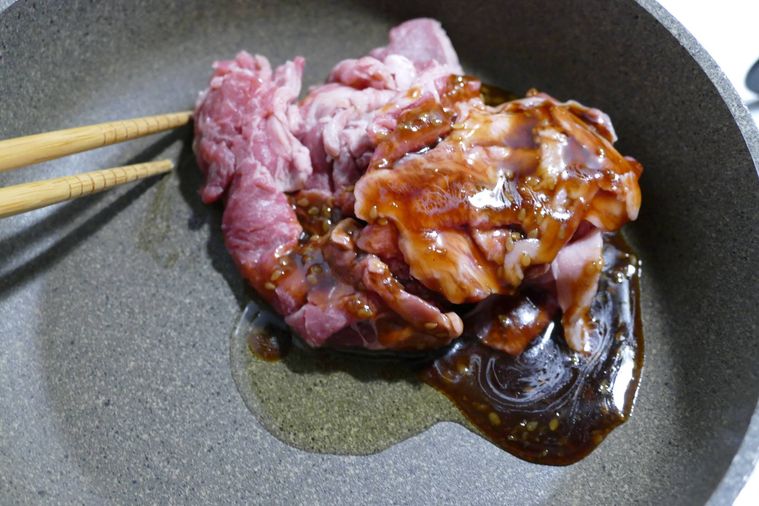 フライパンのなかで牛こま肉、ごま油、焼肉のたれを箸で混ぜる様子