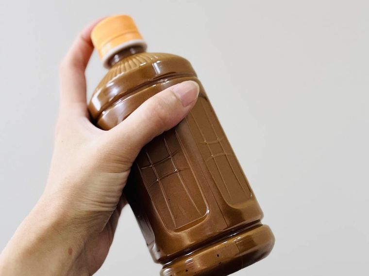 インスタントコーヒー、砂糖、ぬるま湯が入ったペットボトルをシェイクしている様子