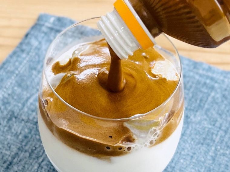 ミルクが入ったグラスにコーヒークリームをそそいでいる様子