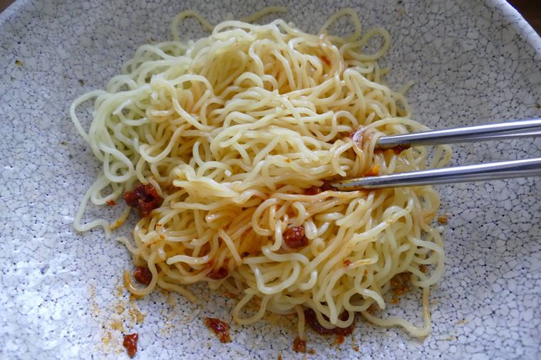 麺とコチュジャン、ごま油、白すりごまを箸で和える様子
