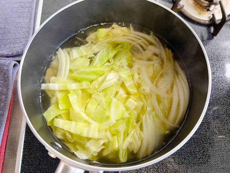 鍋でキャベツと玉ねぎを煮る様子