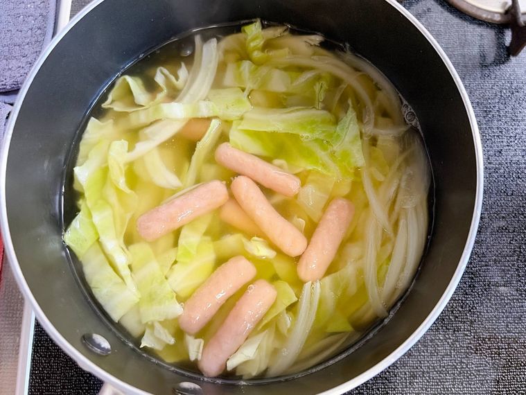 鍋でキャベツと玉ねぎ、ポークビッツを煮る様子