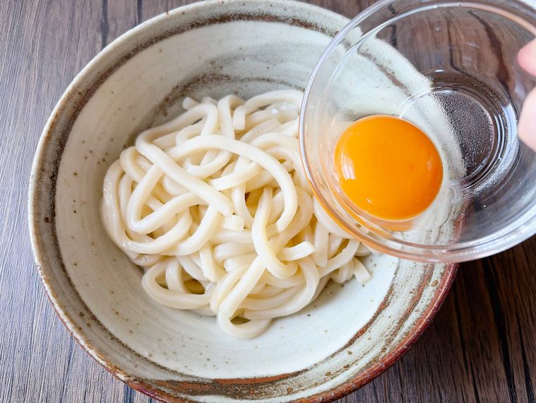 うどんに卵を入れる様子