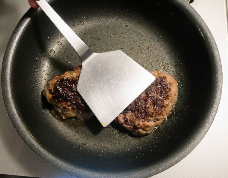 フライ返しでハンバーグの断面を押し付ける様子