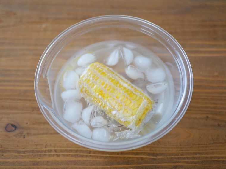 ラップに包んだとうもろこしを氷水で冷ましている様子
