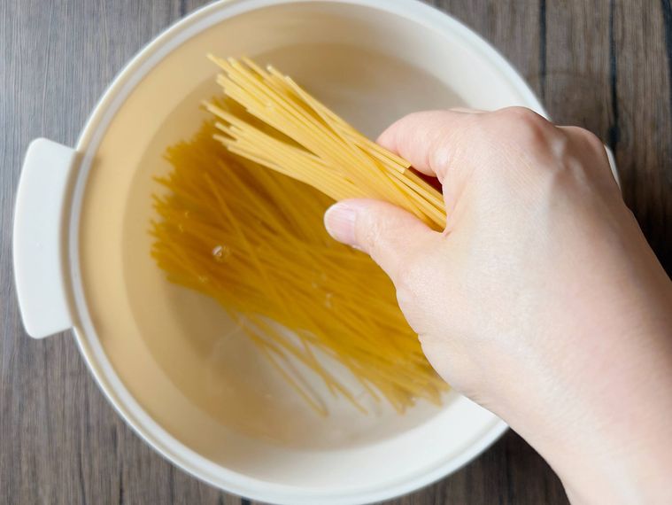 半分に折ったスパゲッティを入れる様子