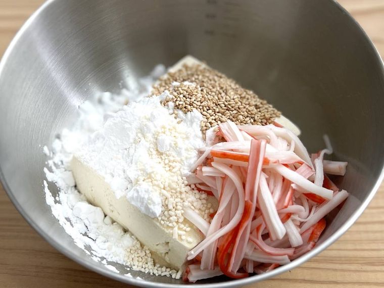 ボウルに豆腐、カニ風味かまぼこ、白いりごま、調味料を入れた様子