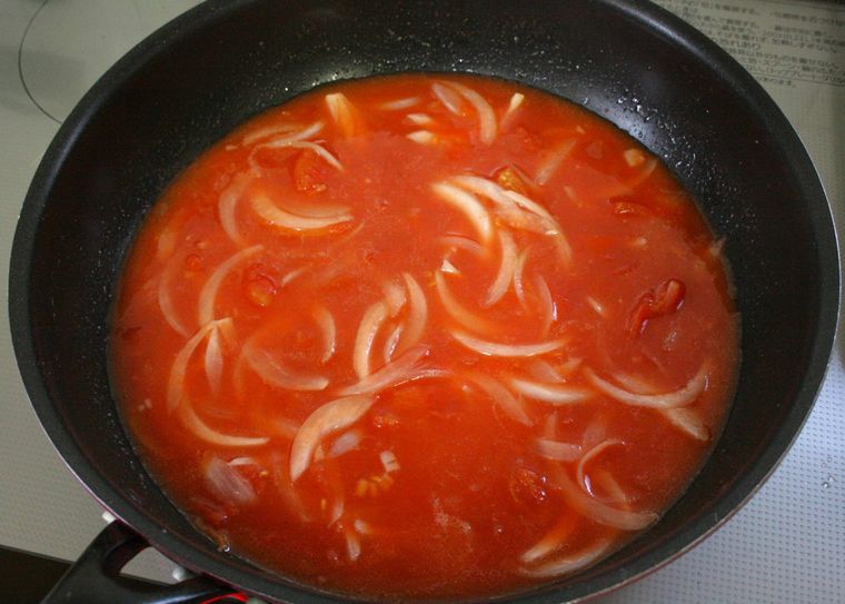 玉ねぎを炒めたフライパンにカットトマト缶や水を入れた様子