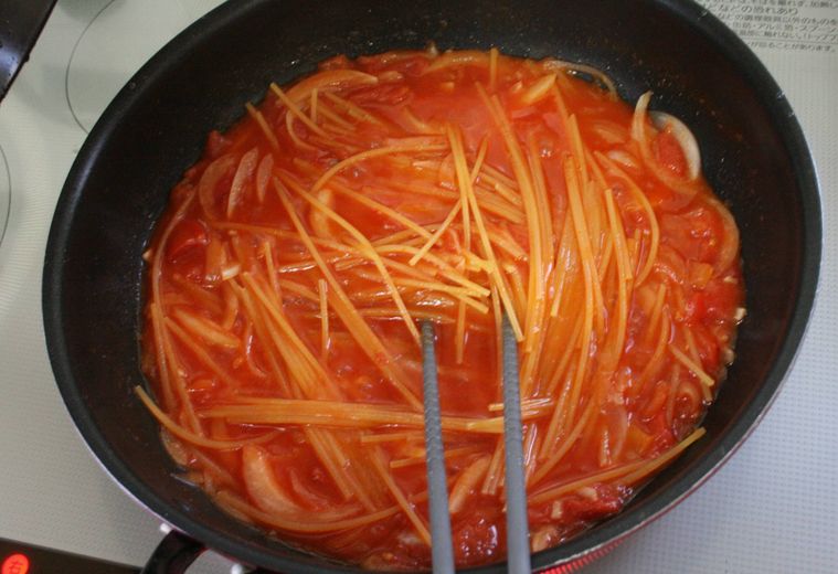フライパンでゆでているスパゲッティを混ぜている様子