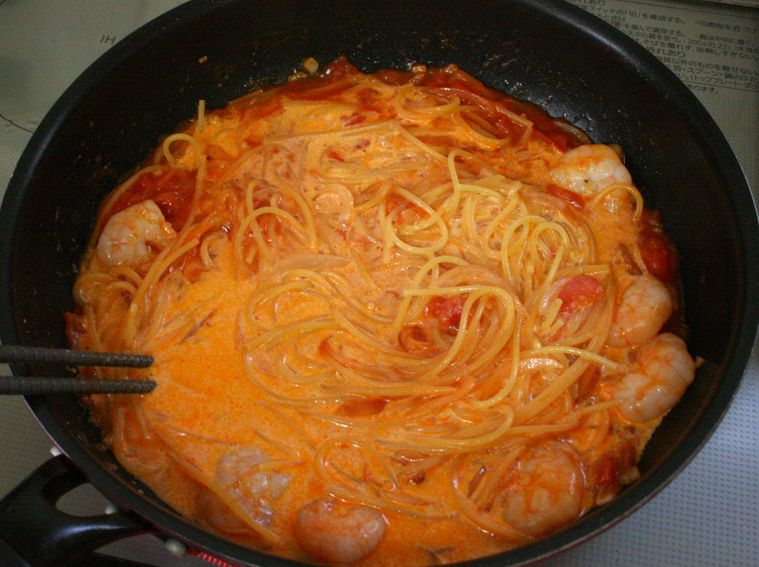 フライパンでエビトマトクリームパスタを作っている様子