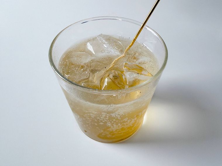 グラスに入ったクラフトコーラをマドラーで混ぜる様子