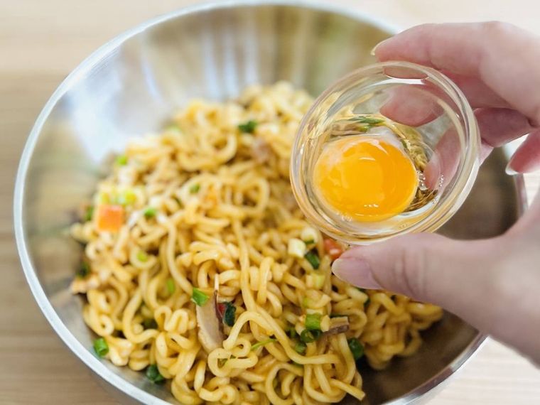 まぜそばに卵黄をのせようとしている様子