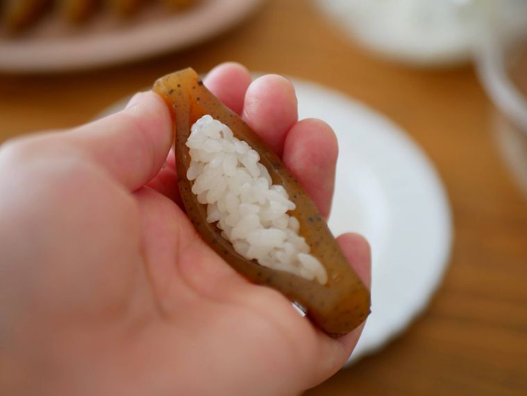 甘辛く煮たこんにゃくに酢飯を詰める様子