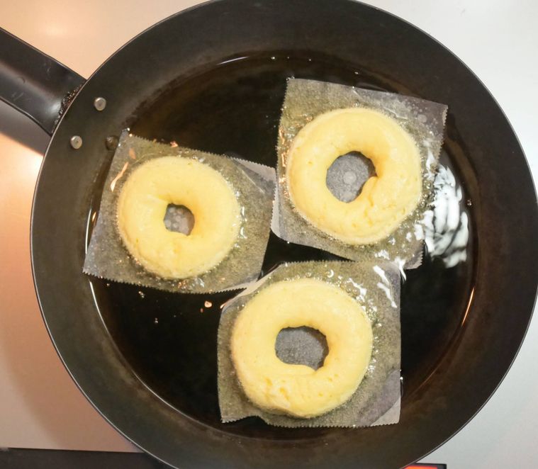 クッキングシートにのせたドーナツ生地を、フライパンで揚げ焼きする様子
