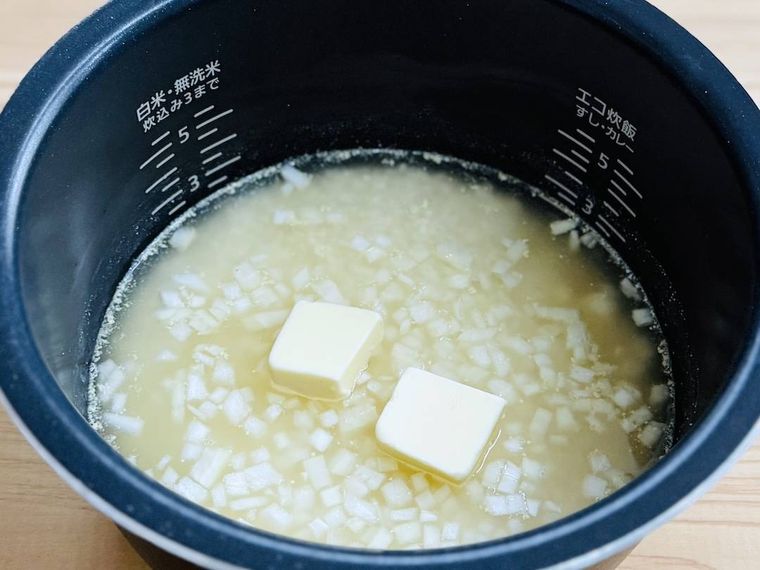 炊飯釜に米、水、コンソメ、玉ねぎ、バターを入れた様子