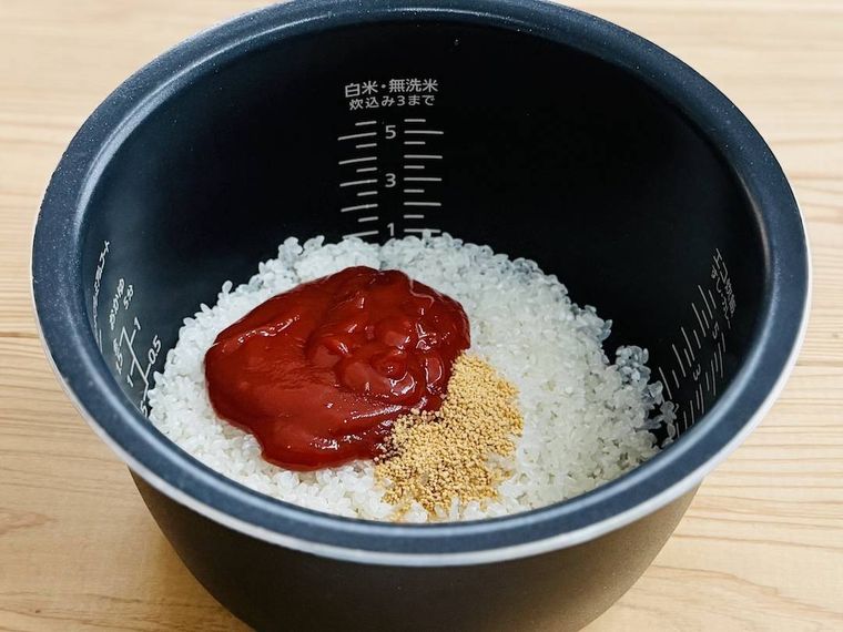 炊飯釜に、米、ケチャップ、コンソメを入れた様子