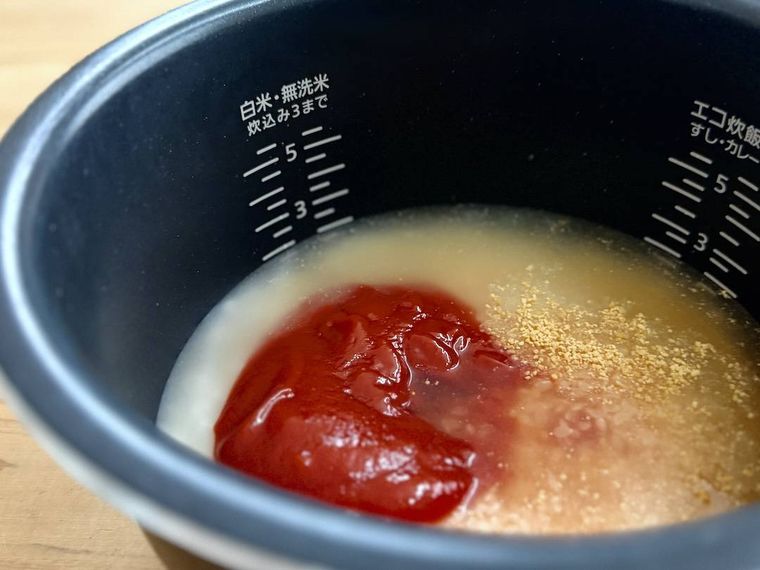 炊飯釜に、米、ケチャップ、コンソメ、水を入れた様子