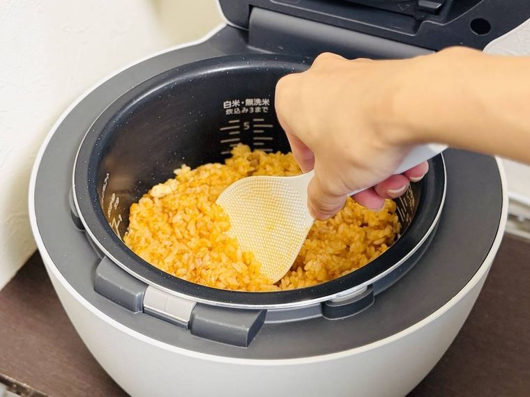 炊飯器で炊いたチキンライスをしゃもじで混ぜている様子