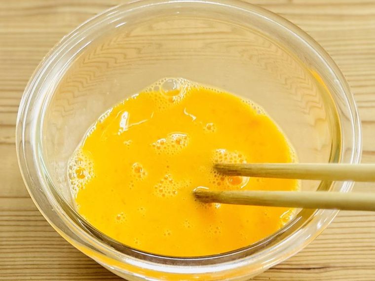 菜箸で卵液をかき混ぜている様子