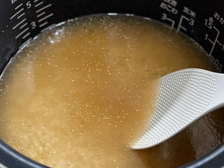 炊飯釜に米、調味料、水を入れ、かき混ぜている様子