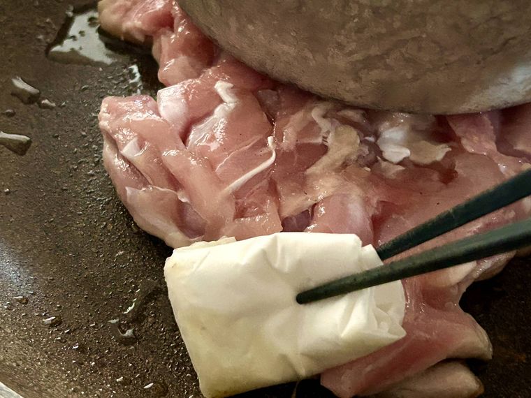 鶏もも肉から出た脂を拭き取っているところ