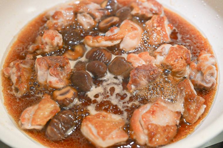 フライパンに入った煮込み中の鶏もも肉と甘栗