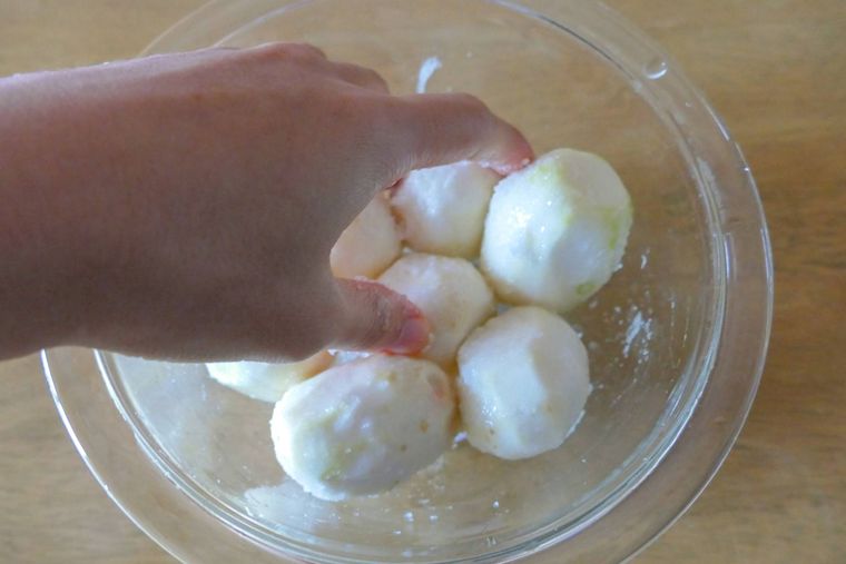 皮を剥いた里芋に手で塩をもみ込む様子