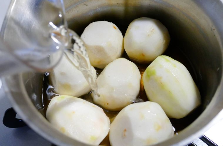 里芋と調味料が入っている鍋に水を注ぐ様子