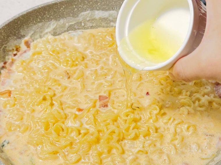 牛乳と水で煮た辛ラーメンに卵黄を加えている様子
