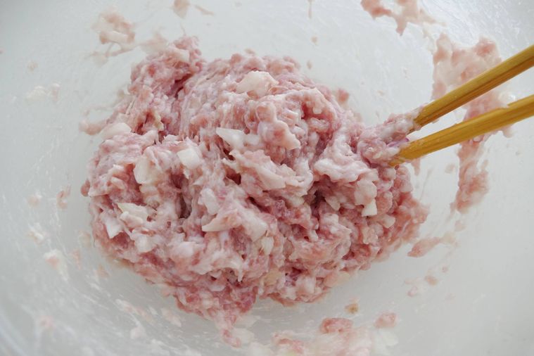 玉ねぎ入りの肉だねを箸で混ぜる様子