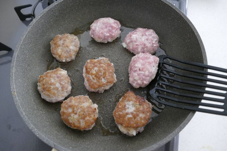 こんがり色づいた肉だねをフライ返しで返す様子