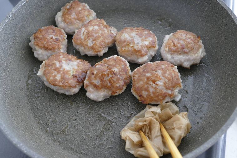 つくねをこんがり焼き、出てきた脂をキッチンペーパーで拭く様子