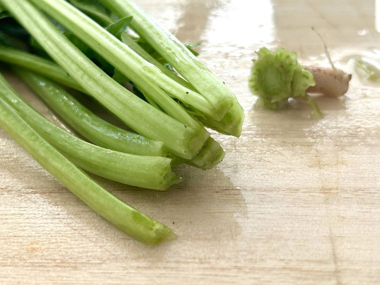 ほうれん草の根元に十字の切れ込みを入れているところ
