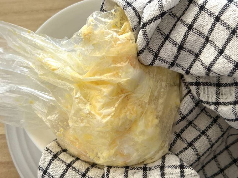 電子レンジから取り出したたまごサラダをふきんでおおって手でもんでいるところ