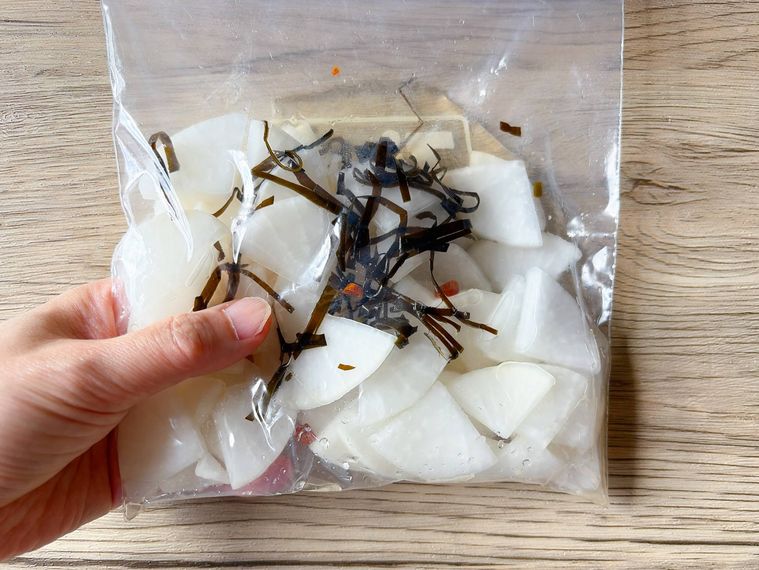 ジッパー付き保存袋に入った大根と調味料をもみ込む様子