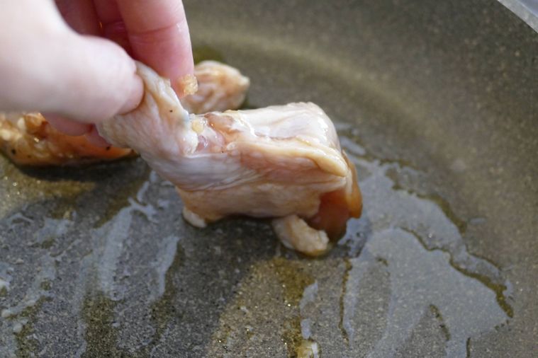 鶏手羽元の皮目を下にしてフライパンに並べる様子