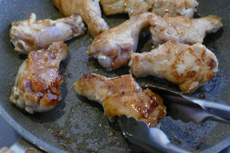 こんがり色づくまで焼いた鶏手羽元をトングで返す様子