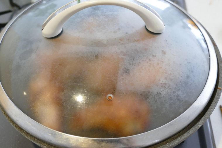鶏手羽元が入っているフライパンに蓋をして蒸し焼きにする様子