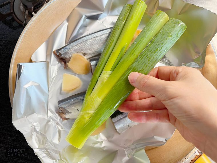 ホイルシートを敷いたフライパンにさんまとしょうが、長ねぎをのせたもの
