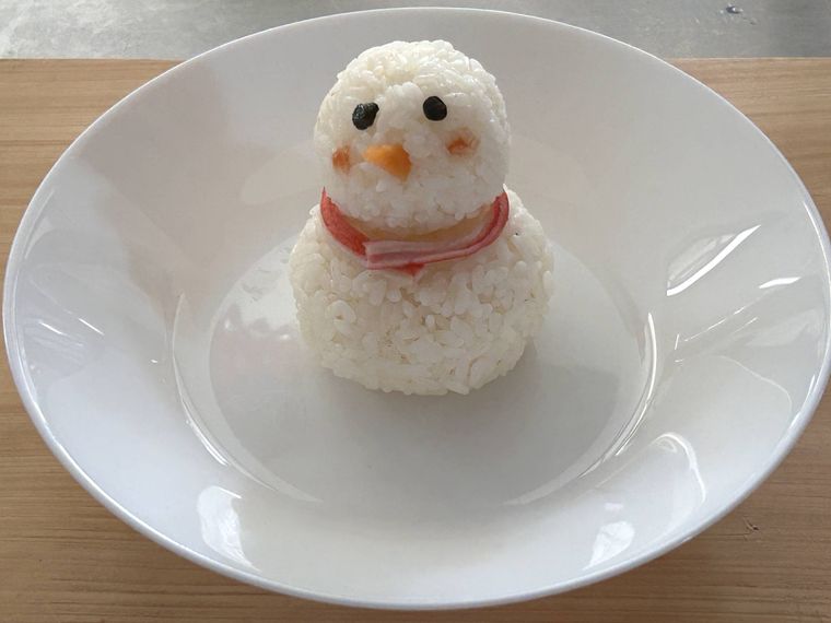 皿の中央にごはんの雪だるまを並べ、海苔やカニ風味かまぼこで飾り付けたところ