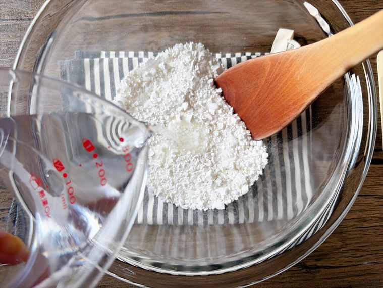 白玉粉と砂糖が入った耐熱ボウルに水を加える様子