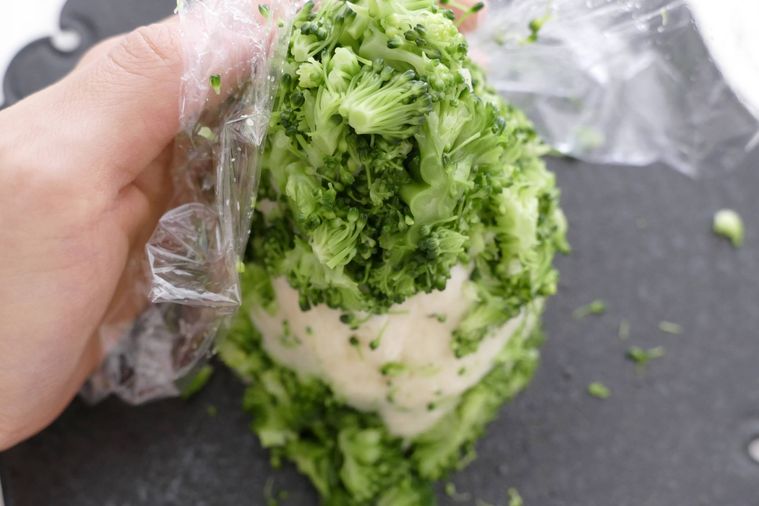 ラップごしに刻んだブロッコリーをポテトサラダに付ける様子